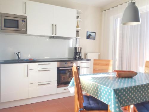 朱列斯拉赫Kurparkcarree - Ferienwohnung "Amber"的厨房配有白色橱柜和带蓝色桌布的桌子。