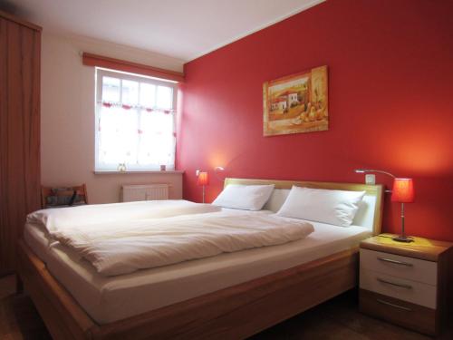 奥斯赛拜-屈隆斯博恩Ferienwohnung Ostseeblick的一间卧室设有一张红色墙壁的大床