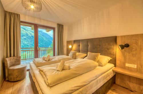 卡普伦Ski-in Ski-out Chalet Maiskogel 17A - by Alpen Apartments的一间卧室设有一张大床和大窗户