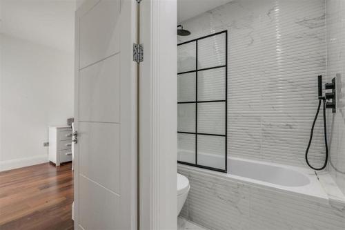 伦敦Modern Majesty 3 Bed 3 Bath House in London的带淋浴和卫生间的白色浴室