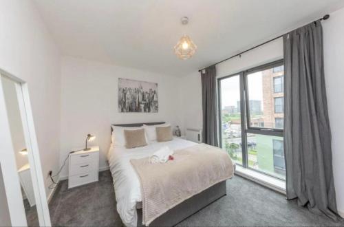 曼彻斯特NovaNest Salford Apartment的一间卧室设有一张床和一个大窗户