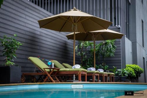仰光Sayarsan Hotel Yangon的一组椅子和遮阳伞,位于游泳池旁