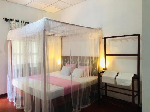 坦加拉Sumudu Modern Villa的一间卧室配有一张带粉红色床单的天蓬床