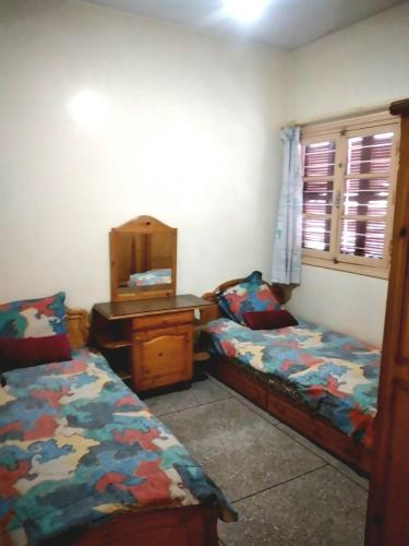 梅克内斯Appartement à Meknès的一间卧室配有两张床、一张桌子和一面镜子