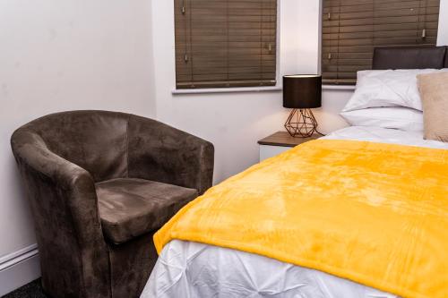 考文垂Divine Stay的一间卧室配有椅子和一张黄色毯子