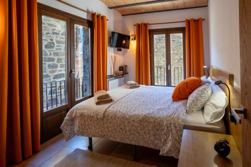 坎普罗东Lo Petit Refugi的一间卧室配有床和橙色窗帘的窗户