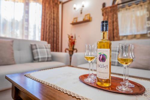 兹拉蒂博尔Vikendica Životić的桌子上放有一瓶葡萄酒和两杯酒