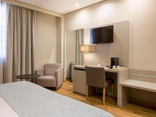 洛格罗尼奥卡尔顿里奥哈美居酒店的酒店客房,配有一张床、一张桌子和椅子