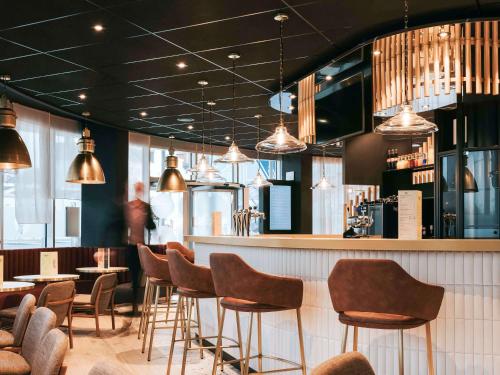 昂热Novotel Angers Centre Gare的一间带椅子的餐厅和一间灯光酒吧
