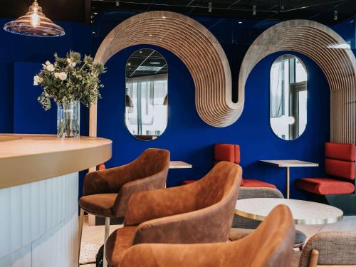 昂热Novotel Angers Centre Gare的餐厅拥有蓝色的墙壁、椅子和镜子