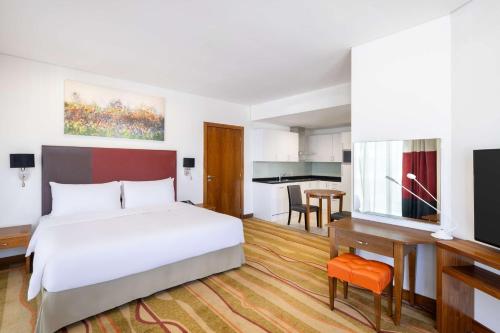 吉达Al Andalus Mall Hotel的一间带一张床和一张书桌的卧室和一间厨房