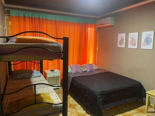 伊瓜苏港Guembe al Rio Hostel的一间卧室设有两张双层床和橙色窗帘