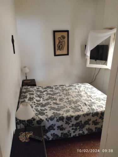马德普拉塔Alquiler Temporada Casa 2 dormitorios para 6 personas的一间卧室配有一张床和一张带台灯的桌子