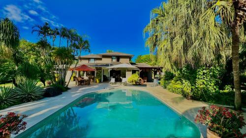 塔马兰Villa Petit Tamarin : piscine bar et grand jardin tropical的棕榈树屋前的游泳池
