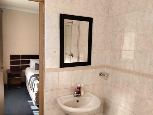米德尔堡Turquoise View Guesthouse的一间带水槽和镜子的浴室以及一张床