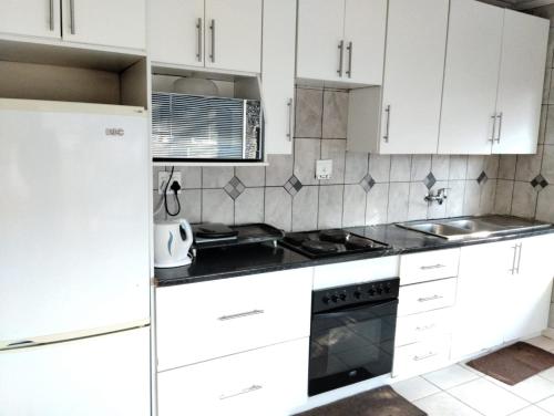 米德尔堡Turquoise View Guesthouse的厨房配有白色橱柜和炉灶烤箱。