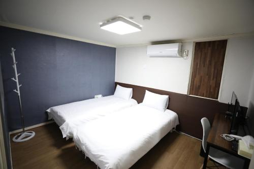 首尔Hotel Golden Hill的小型客房配有2张床、书桌和1张sidx单人床。