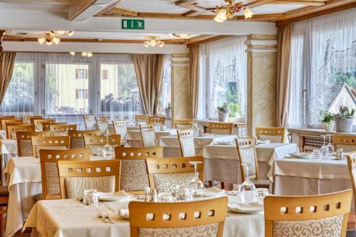 莫尔韦诺丽城阿尔卑斯山健康与美容度假酒店的餐厅设有白色的桌椅和窗户。
