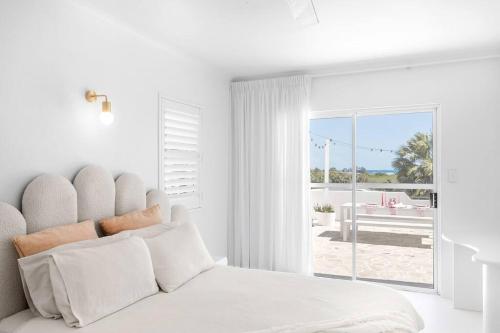 麦凯WhitsunStays - The Cyclades的白色卧室设有一张床,享有庭院的景色