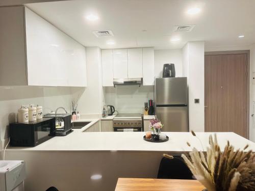 沙迦Modern Sanctuary W/ Pool & Gym access的厨房配有白色的柜台和冰箱。