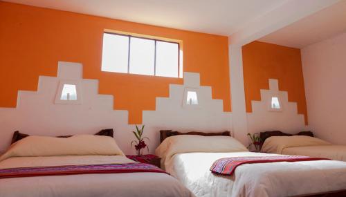 Comunidad ChallapampaHostal Margarita Isla del Sol Norte comunidad Challapampa的橙色墙壁的客房内的两张床