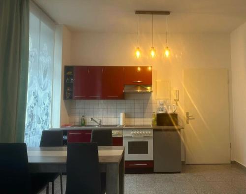 马格德堡Stilvolles Zuhause的厨房配有红色橱柜和一张桌子