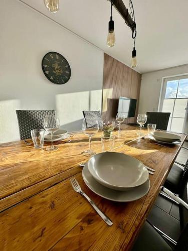 不来梅港Stilvoll eingerichtetes Ferienhaus in ruhiger Lage的一张木桌,上面放有盘子和酒杯