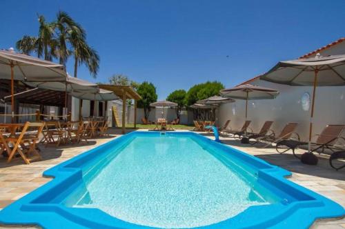马蒂尼奥斯Hostel Costa Terral的一个带椅子和遮阳伞的蓝色游泳池