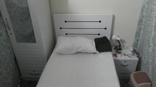 迪拜Ruby Star Male Hostel Dubai的一间小卧室,配有一张白色的床和床头板
