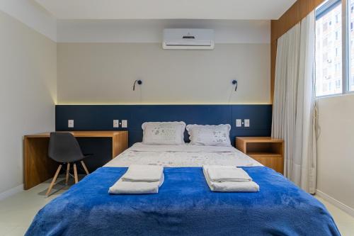 弗洛里亚诺波利斯Confortável Studio com 46,72m²的一间卧室配有一张大蓝色的床和毛巾
