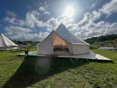 拉耶North Shore Glamping / Camping Laie, Oahu, Hawaii的天空中阳光明媚的田野上的两个帐篷