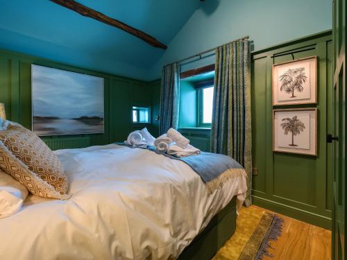 康福斯Three Peaks Barn的一间卧室设有绿色的墙壁和一张带毛巾的床