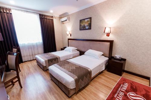 塔什干Simma Hotel Spa & Waterpark的酒店客房设有两张床和窗户。