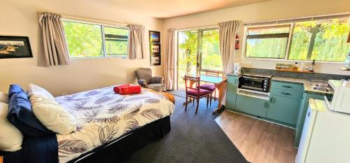 Upper Moutere水车度假屋的一间卧室配有一张床,厨房配有窗户