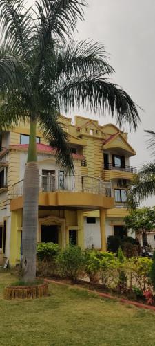 RāmtekGaurav Resort的一座黄色的大建筑,前面有一棵棕榈树