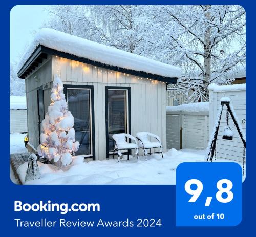 罗瓦涅米Guest house - Northern tealight的雪中有一棵圣诞树的小房子