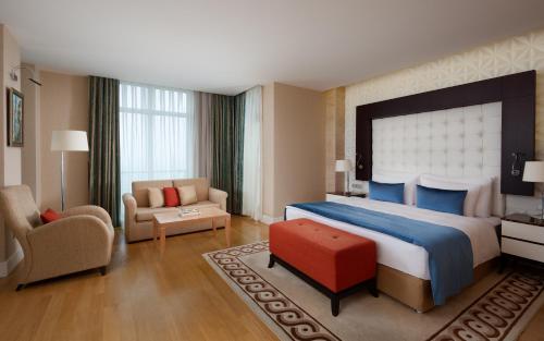 巴库Badamdar Hotel and Residences的酒店客房带一张大床和一把椅子