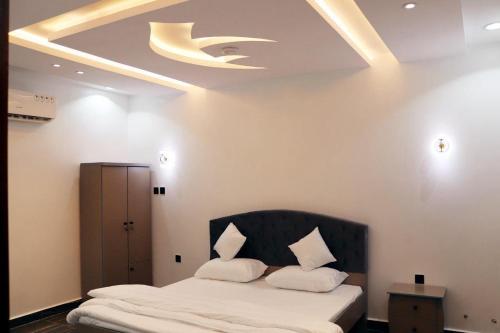 Sūq al Aḩadنيلوفر بيتي的一间卧室配有一张带黑色床头板和天花板的床。