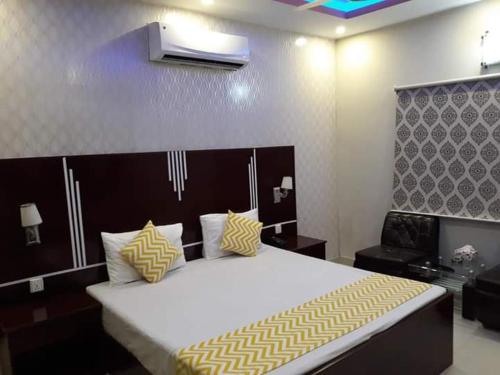 卡拉奇Pramier Inn Near Agha Khan Hospital的一间卧室配有一张带黄色和白色枕头的大床