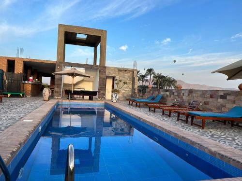 卢克索Nile Panorama Hotel的大楼旁的游泳池配有长椅和遮阳伞