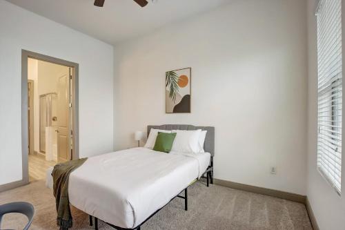 坦培Modern 2BR CozySuites on Town Lake waterfront 12的白色卧室配有一张带绿色枕头的床