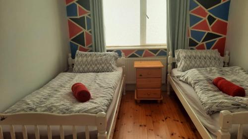 科芙Cobh Rambler的小房间设有两张带红色枕头的床