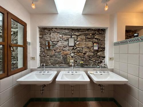 FalmentaCasa di Lui e Luise - Yoga - Ayurveda - Kräuter - Natur的一间带三个水槽和石墙的浴室