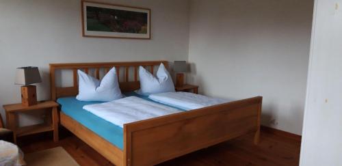 Bugewitz130qm-grosse-Ferienwohnung-am-Naturschutzgebiet-15-Min-bis-zum-Stettiner-Haff-PKW的一间卧室配有带白色枕头的木床