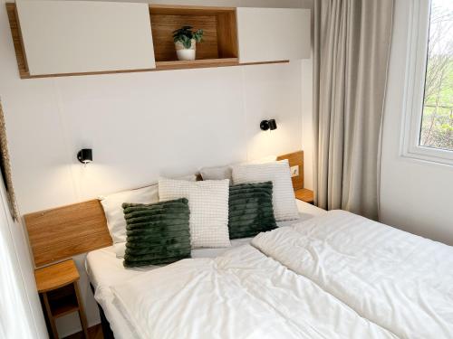 雷讷瑟Ocean Garden Chalet Renesse的卧室配有带绿色枕头的白色床