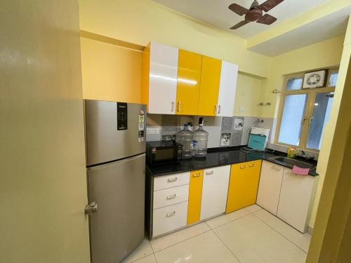 加尔各答Merlin Legacy的厨房配有黄色和白色的橱柜和冰箱。