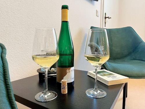 马林诺维德Pension 1595 im Weingut Botzet的桌子上放有一瓶葡萄酒和两杯酒