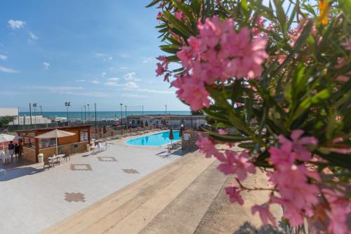 维耶斯泰Village La Canzone del Mare的享有带游泳池和粉红色鲜花的度假村景色