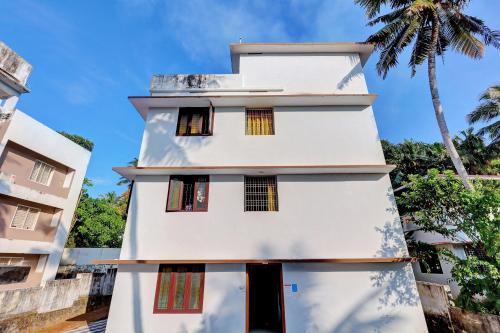 TrippapurCollection O Prashant Stays的白色的建筑,有窗户和棕榈树
