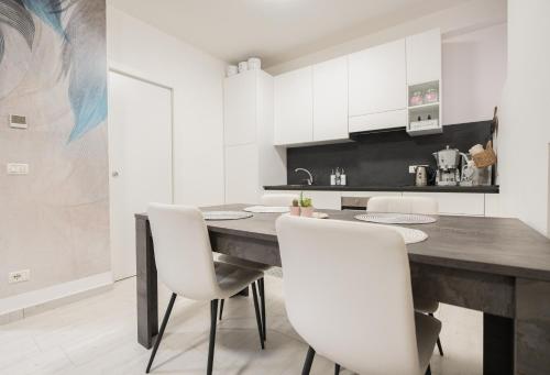 萨罗C-Apartment Lake Garda的厨房配有木桌和白色椅子